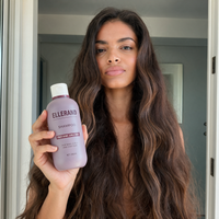 A woman with soft wavy hair holding the Ellerand Clean Start Shampoo